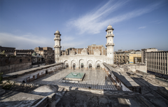Exterior view of the restored Mohabbat Khan Mosque showcasing Mughal-era stucco, plaster, and painted decorations on the lower walls