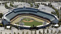 Aerial view of Dodger Stadium in Los Angeles, California, surrounded by green hills under a cloudy sky