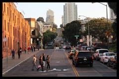 Cable car descending Hyde Street with tourists jaywalking near Argonaut Hotel in San Francisco
