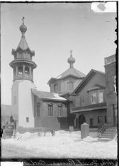 Winter view of Holy Trinity Church in Chicago with a complete bell tower and a young boy enjoying the snow