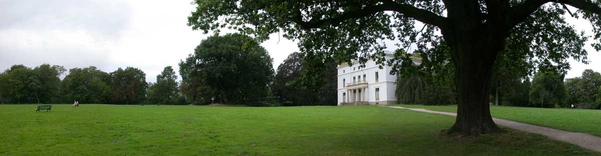 Panoramic view of the Jenisch park in Hamburg with lush green landscape and historical buildings under clear blue sky