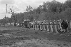 Black and white photograph of a military band walking in front of a hearse during a reburial ceremony at Antjol military cemetery in Ancol, Batavia, 1946
