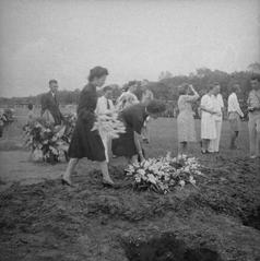 Family and friends laying wreaths and bouquets at the graves of 24 people executed by the Japanese, during a reburial ceremony at Antjol military cemetery