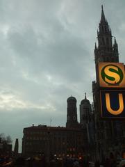 March evening view of Marienplatz in Munich with Frauenkirche towers, Neues Rathaus, and S-Bahn and U-bahn signs