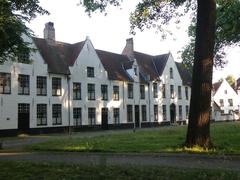 Begijnhof courtyard in Bruges with historic brick buildings and cobblestone ground under clear sky