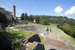 Ancient Roman theatre in Fiesole surrounded by trees under a blue sky