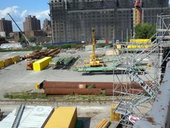 Marshalling yard with green rebars and construction materials under a mostly sunny sky