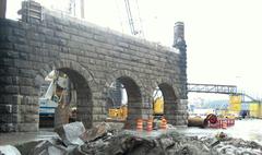 Stonework pier of partly demolished old bridge viewed from under new bridge approach
