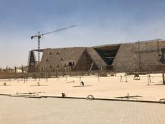 Grand Egyptian Museum building at Giza with large glass facade and surrounding greenery