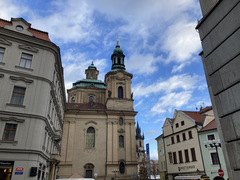 Street scene in Prague with memorial flowers a day after a shooting, symbolizing life continuing