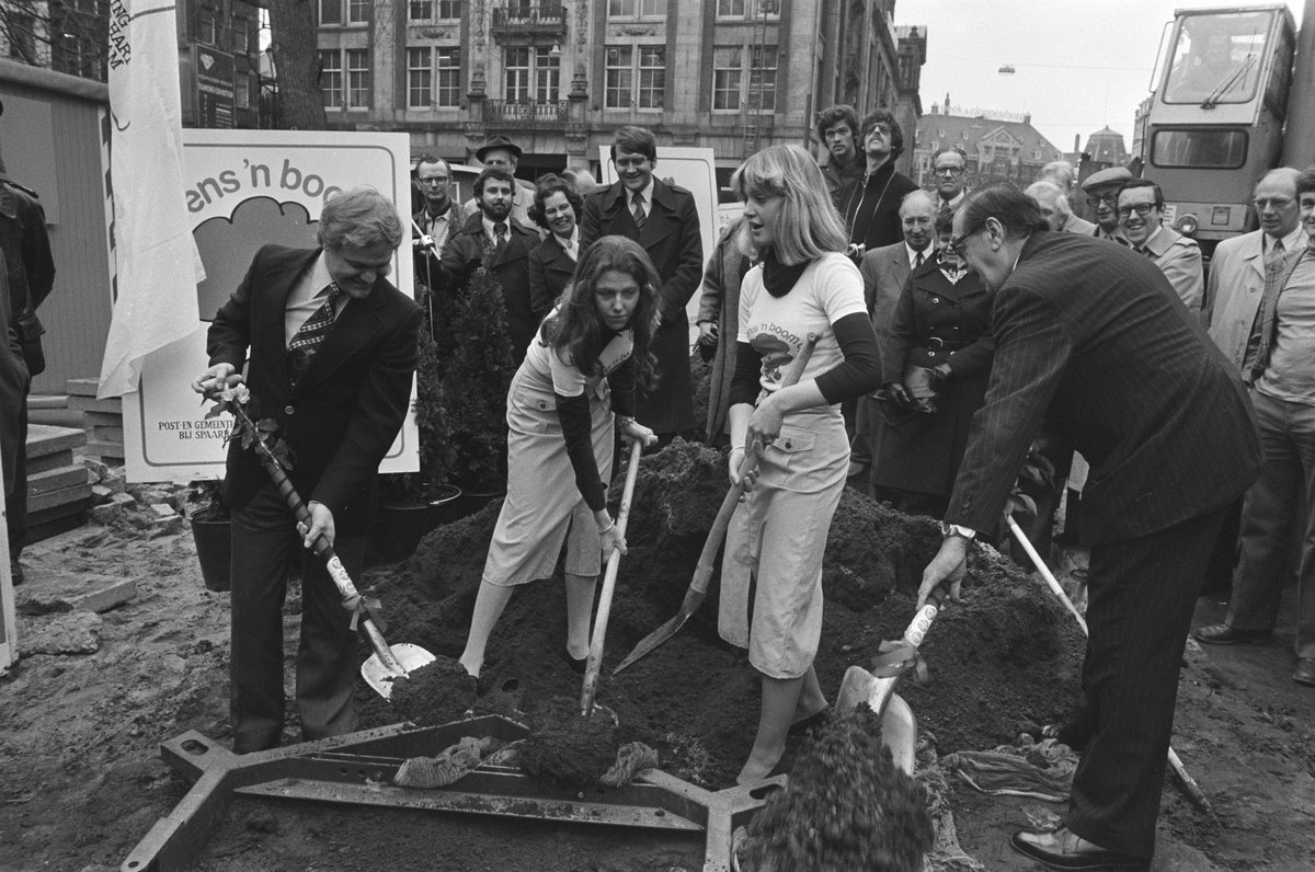 Wethouders Cees de Cloe and Emile Schüttenhelm planting an elm tree on Beursplein in Amsterdam during a ceremonial event on March 16, 1977