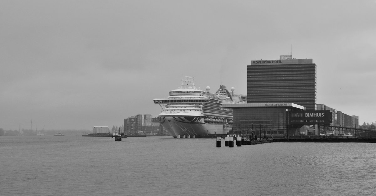 Black and white panoramic view of Het IJ waterfront in Amsterdam with industrial buildings and water