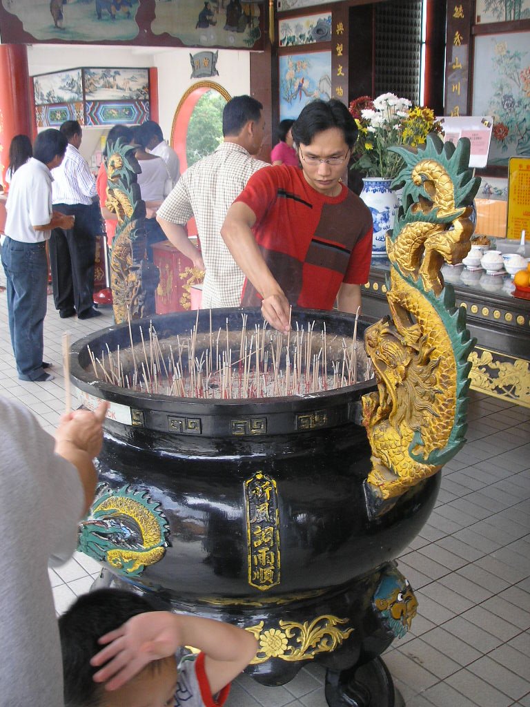 Burning joss sticks at Thean Hou Temple in Kuala Lumpur with colorful traditional decorations