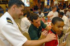 U.S. Navy Chaplain steadying shoulder of a young man as New York Jets linebacker signs shirt during Fleet Week 2007 community event in Times Square Church