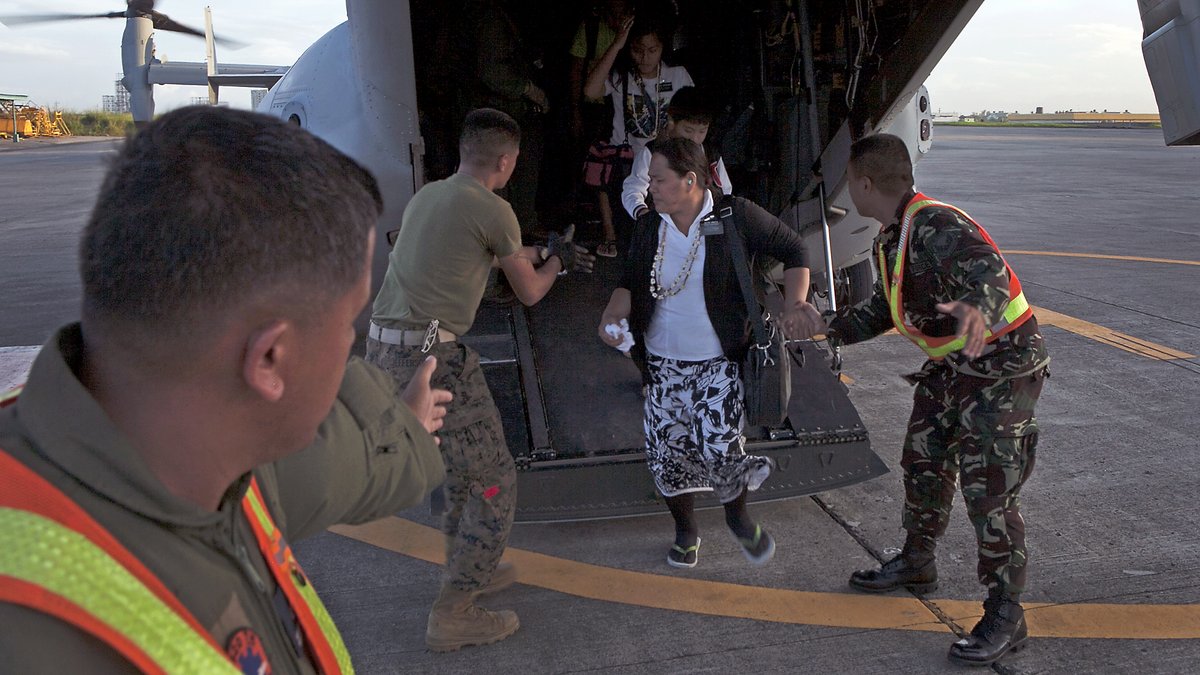 U.S. Marines assisting a Filipino woman off an MV-22B Osprey at Villamor Air Base after Typhoon Haiyan