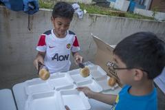 Filipino children volunteer serving food to evacuees at Villamor Air Base after Typhoon Haiyan