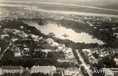 Aerial view of Petit Lac (Return Sword Lake) and its surroundings in Hanoi, 1930, showing shaded promenade, Turtle Pagoda, Ngoc Son Pagoda, European quarter, and Red River in the distance