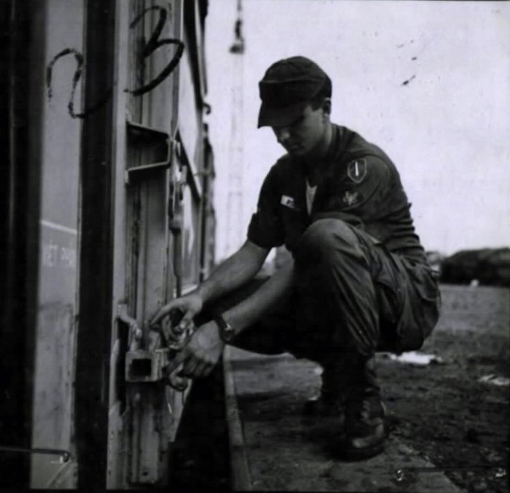Railroad Specialist SP4 James Roose inspecting the lock on a loaded cargo railcar door