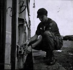 Railroad Specialist SP4 James Roose inspecting the lock on a loaded cargo railcar door