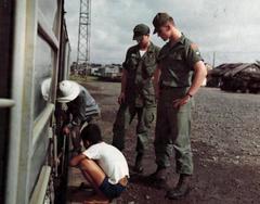 US Army soldiers from the 507th Transportation Company watch Vietnamese laborers prepare a steel loading ramp