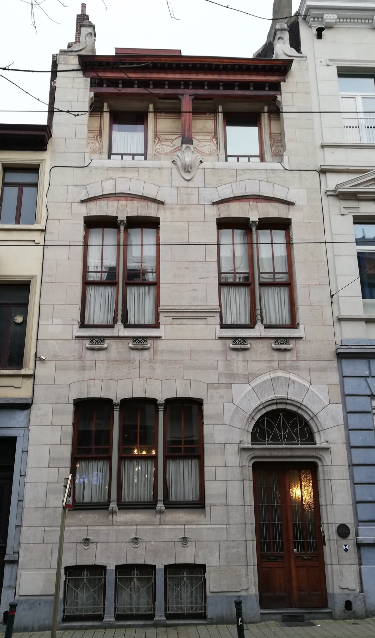 View of Autrique House in Brussels with its distinct brick facade and architectural details under a clear sky