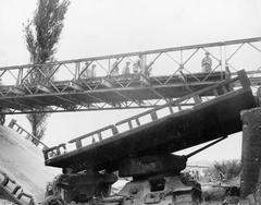 Bailey Bridge constructed over destroyed bridge near Naktong River with knocked-out T-34 tank under it during Korean War