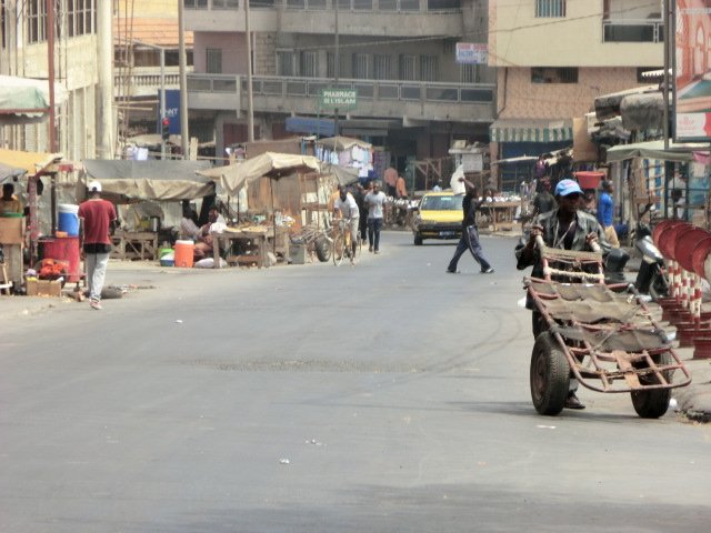 Avenue Jean-Jaurès street view in Dakar with buildings, shops, and vehicles