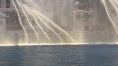 Fountains of Bellagio shooting water jets at night with city lights in the background