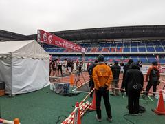 Runners competing in a rainy ekiden relay race at Yokohama Nissan Stadium