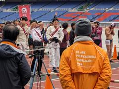 Runners participating in Waseda Ekiden race in rainy weather at Yokohama Nissan Stadium
