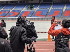 Waseda University Ekiden team running in the rain at Yokohama Nissan Stadium