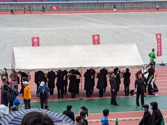 Waseda University Ekiden relay team running in the rain at Yokohama Nissan Stadium