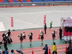 Runners competing in Waseda Ekiden relay race at Yokohama Nissan Stadium in rainy weather