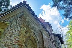 Exterior view of Boyana Church with stone walls and decorative frescoes under a blue sky
