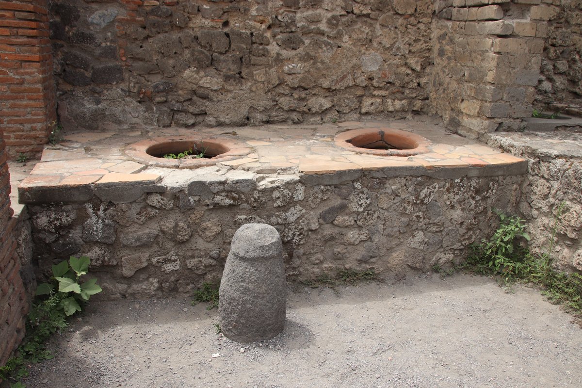 Ancient Roman thermopolium in Pompeii with counter and frescoes