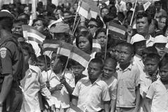 Arrival of Queen Juliana and Prince Bernhard at Jakarta airport greeted by children with flags in black and white photo