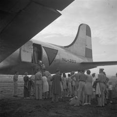 Repatriation at Kemajoran Airport in Batavia, Indonesia in November 1945 featuring a Douglas C-54 Skymaster aircraft with registration NL-303 and passengers