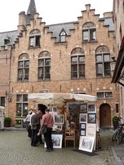 Cozy square in Bruges city center with romantic Duc de Bourgogne hotel, art stalls, and lively terraces serving delicious mussels