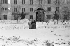 Women carrying bag on back walking in snow in front of building at Kutuzovsky Prospect Moscow 1967