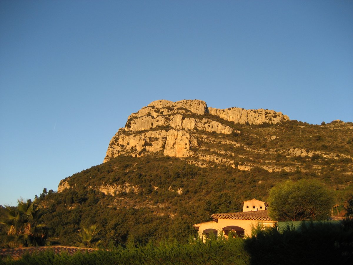 Baou de Saint-Jeannet rocky hill with green vegetation under blue sky