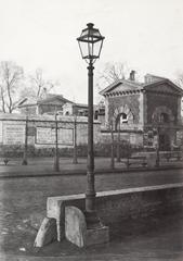 Single lantern on iron lamp post beside low stone parapet