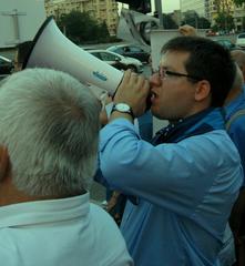Romanian politician Mihail Neamţu shouting political slogan at protest rally in Victoriei Square, Bucharest