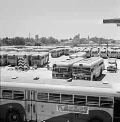 1964 black and white photo of buses parked at a bus depot on Sabbath in Tel Aviv with a TWA building in the background