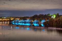 Boat House Row along the Schuylkill River in Philadelphia at dusk with lit-up historic boathouses reflecting in the water