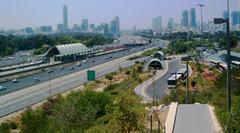 Ayalon Highway and train entering Tel Aviv University railway station with Tel Aviv University station entrance, Dan bus terminal, and Tel Aviv and Ramat Gan skyscrapers in background