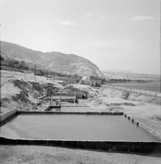 Historic bathhouse with hot springs by the shore of the Sea of Tiberias with water basins in foreground and surrounding hills in Israel