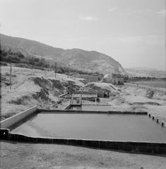 Historic bathhouse with hot springs on the shore of the Sea of Tiberias showing water basins, telephone poles, and surrounding hills