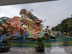 Landscape view of Suoi Tien Park with colorful lotus ponds and traditional Vietnamese architecture under a partly cloudy sky in July 2023