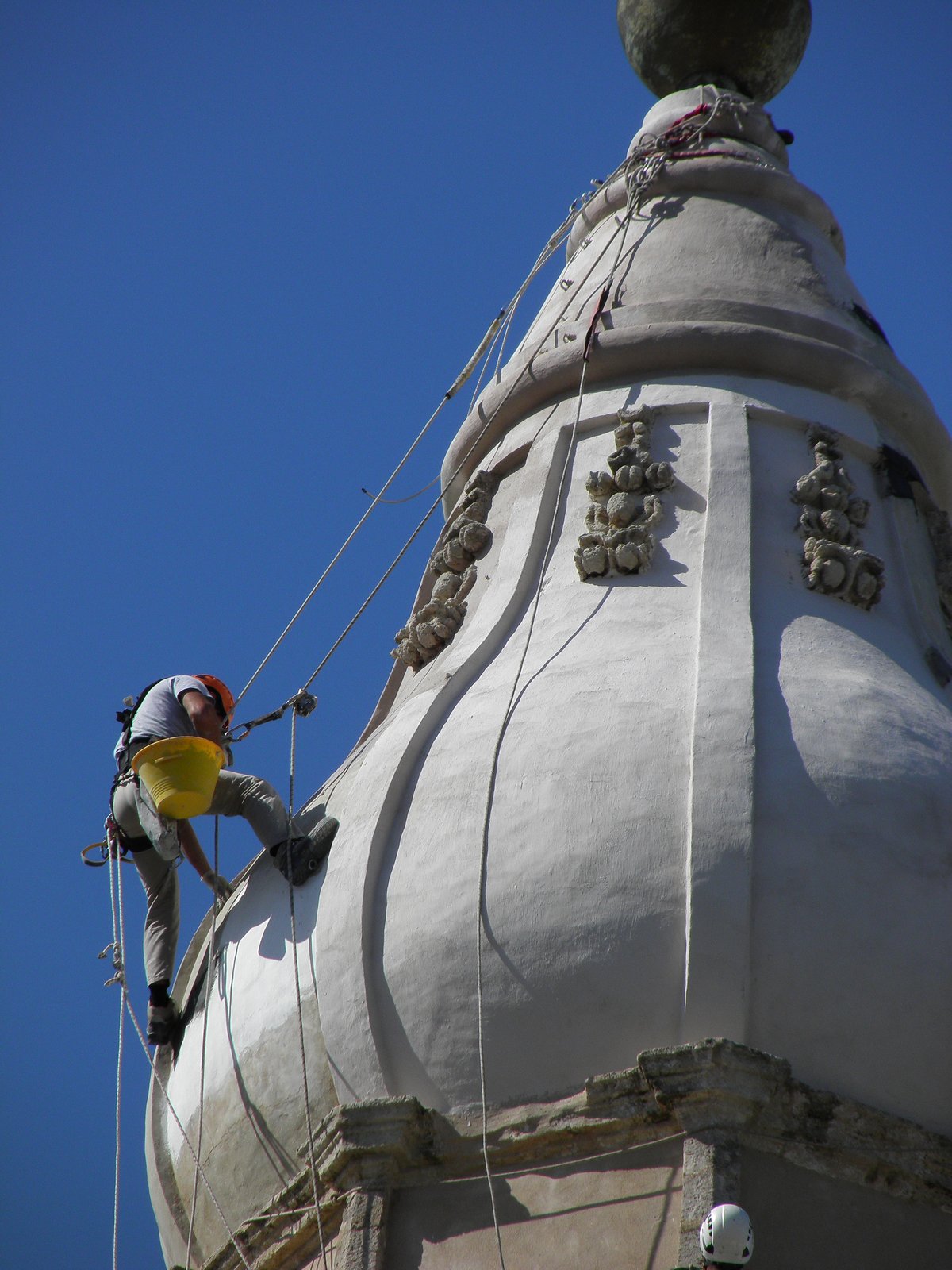 Restorers climbing and working at 65 meters height on the bell tower of Monopoli Cathedral damaged by lightning