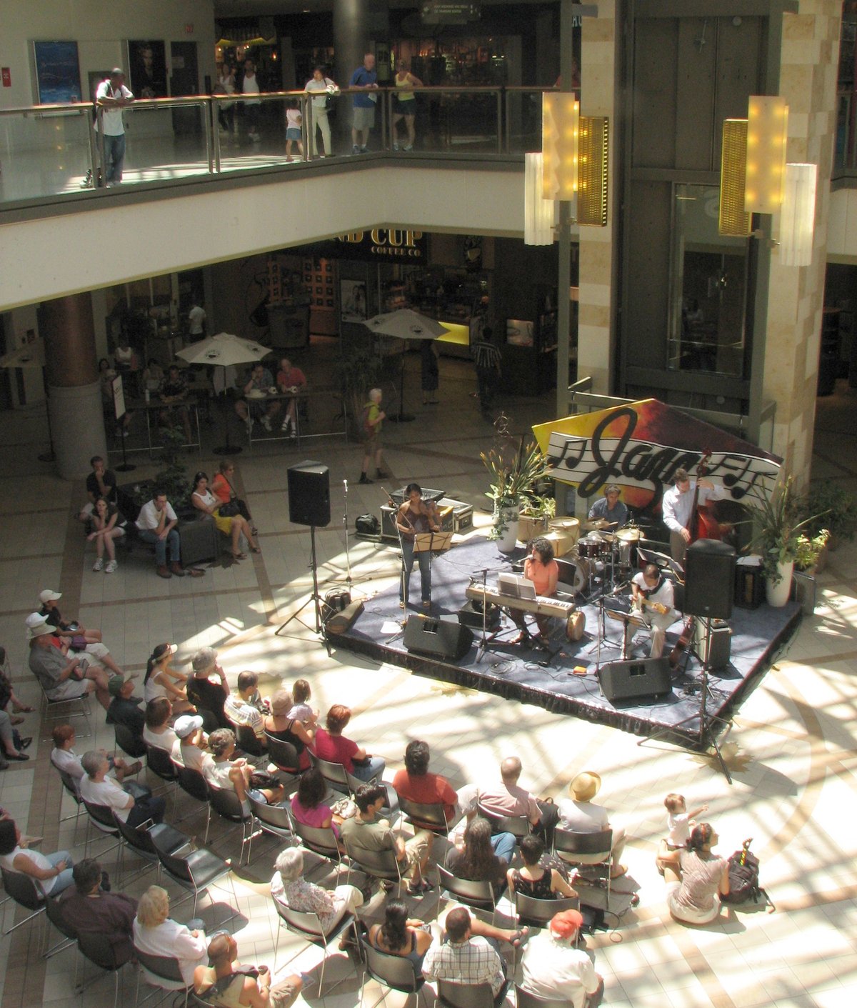 People enjoying outdoor jazz music festival sitting on chairs in front of musicians